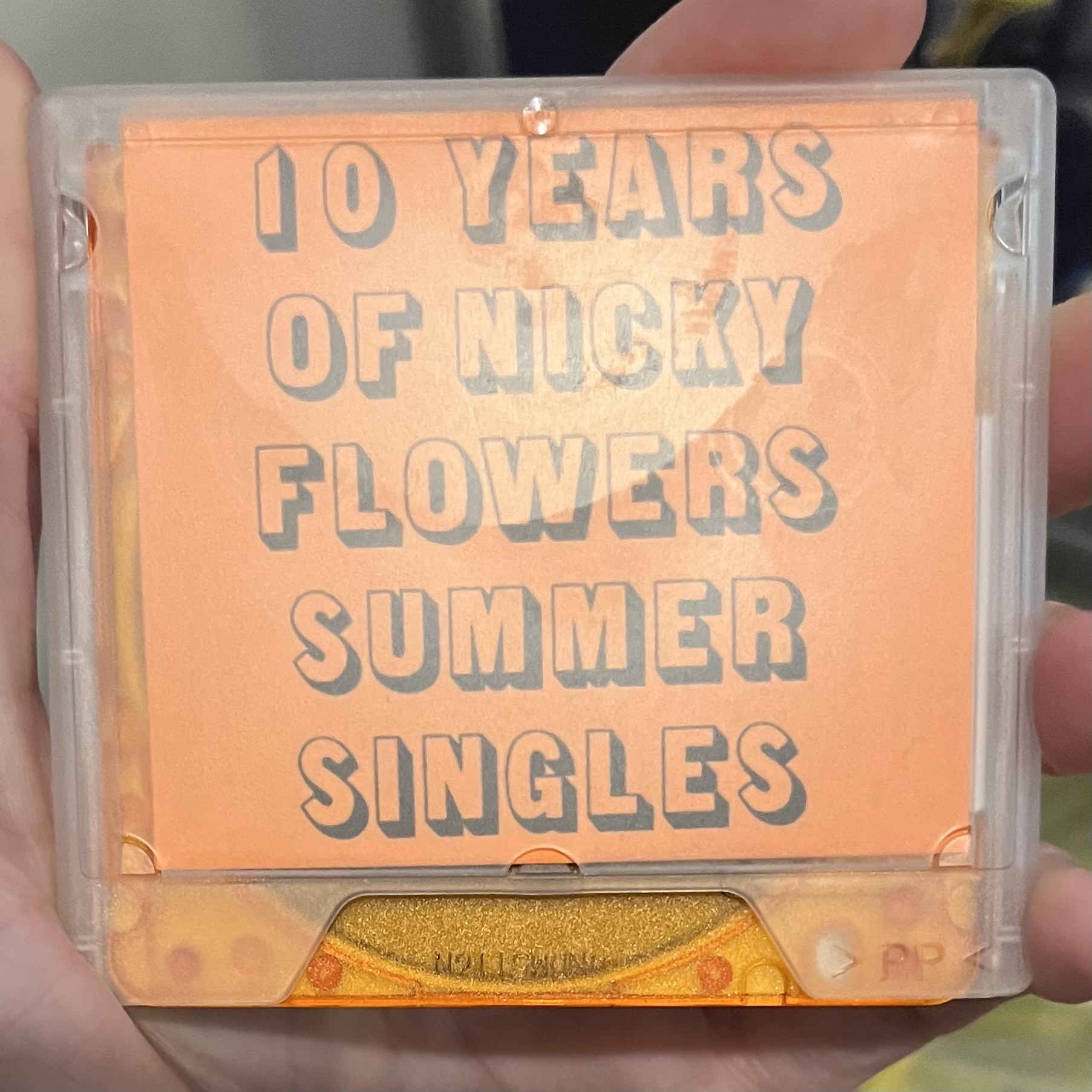 Photo of a minidisc with a label reading “10 Years of Nicky Flowers Summer Singles”