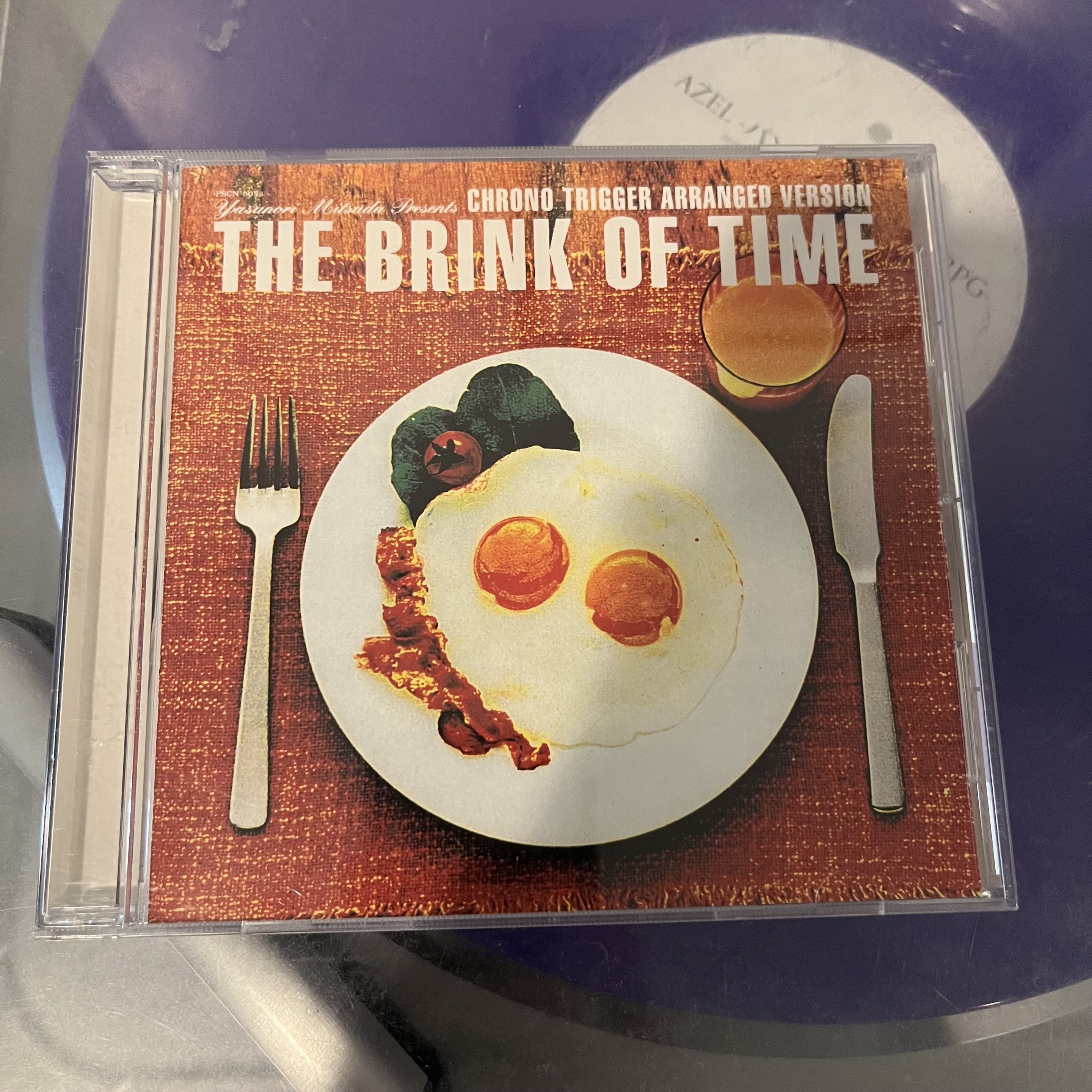 Photo of the jewel case for the album The Brink of Time, featuring a breakfast plate with eggs on it.